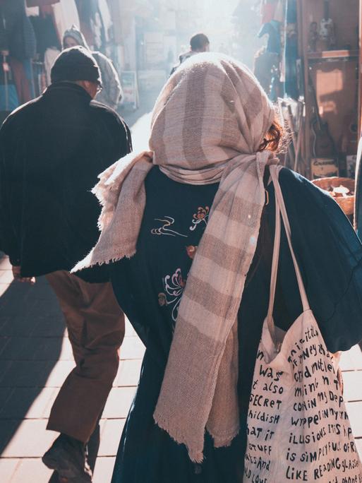 Eine Frau und ein Mann gehen in einer Stadt in Marokko eine Marktgasse entlang. 