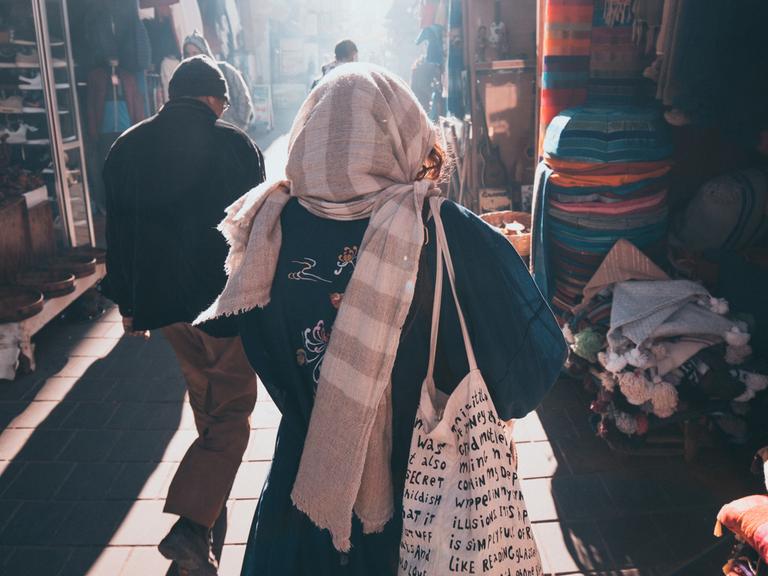 Eine Frau und ein Mann gehen in einer Stadt in Marokko eine Marktgasse entlang. 
