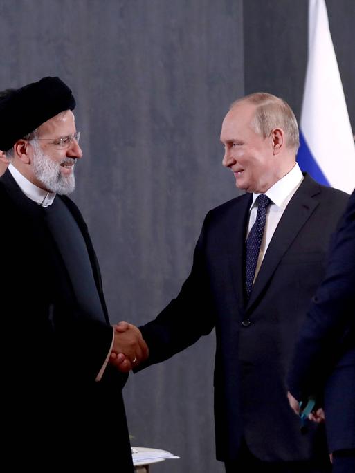 Der iranische Präsident Ebrahim Raisi und Wladimir Putin schütteln sich die Hände bei einem Treffen in Usbekistan, 2022.