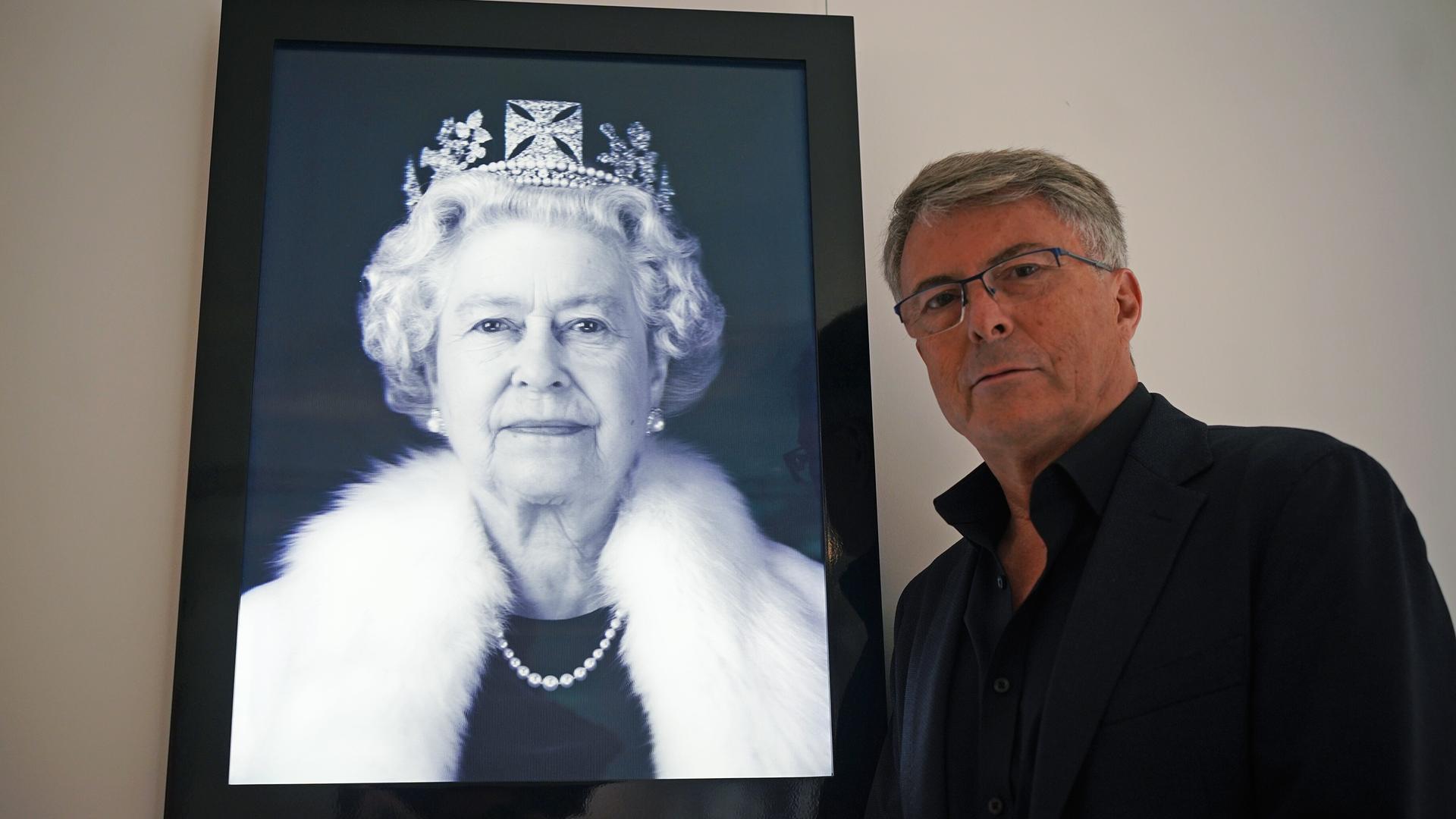 Rob Munday posiert neben einem Werk in Zusammenarbeit mit Chris Levine, "Equanimity: Queen Elizabeth II" (2004). 