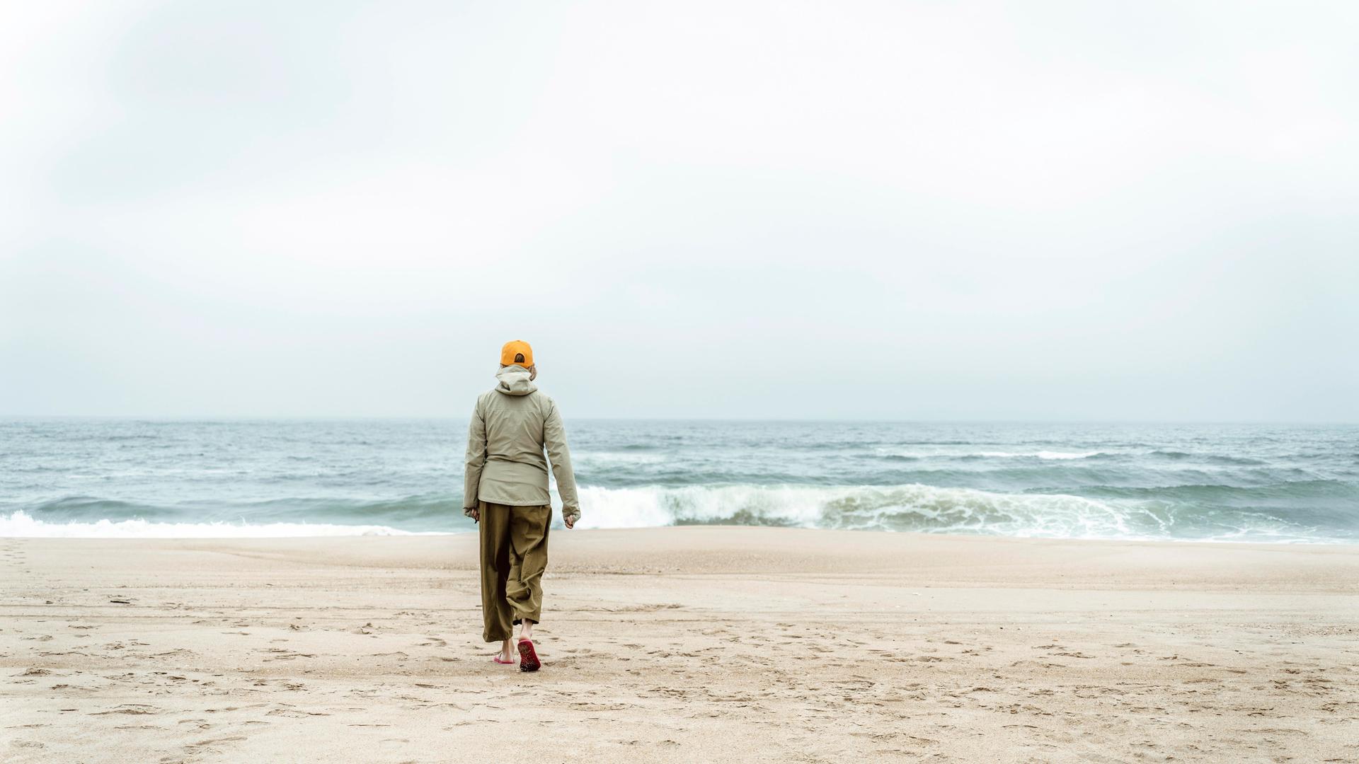 Frau spaziert an einem Strand (Symbolbild)