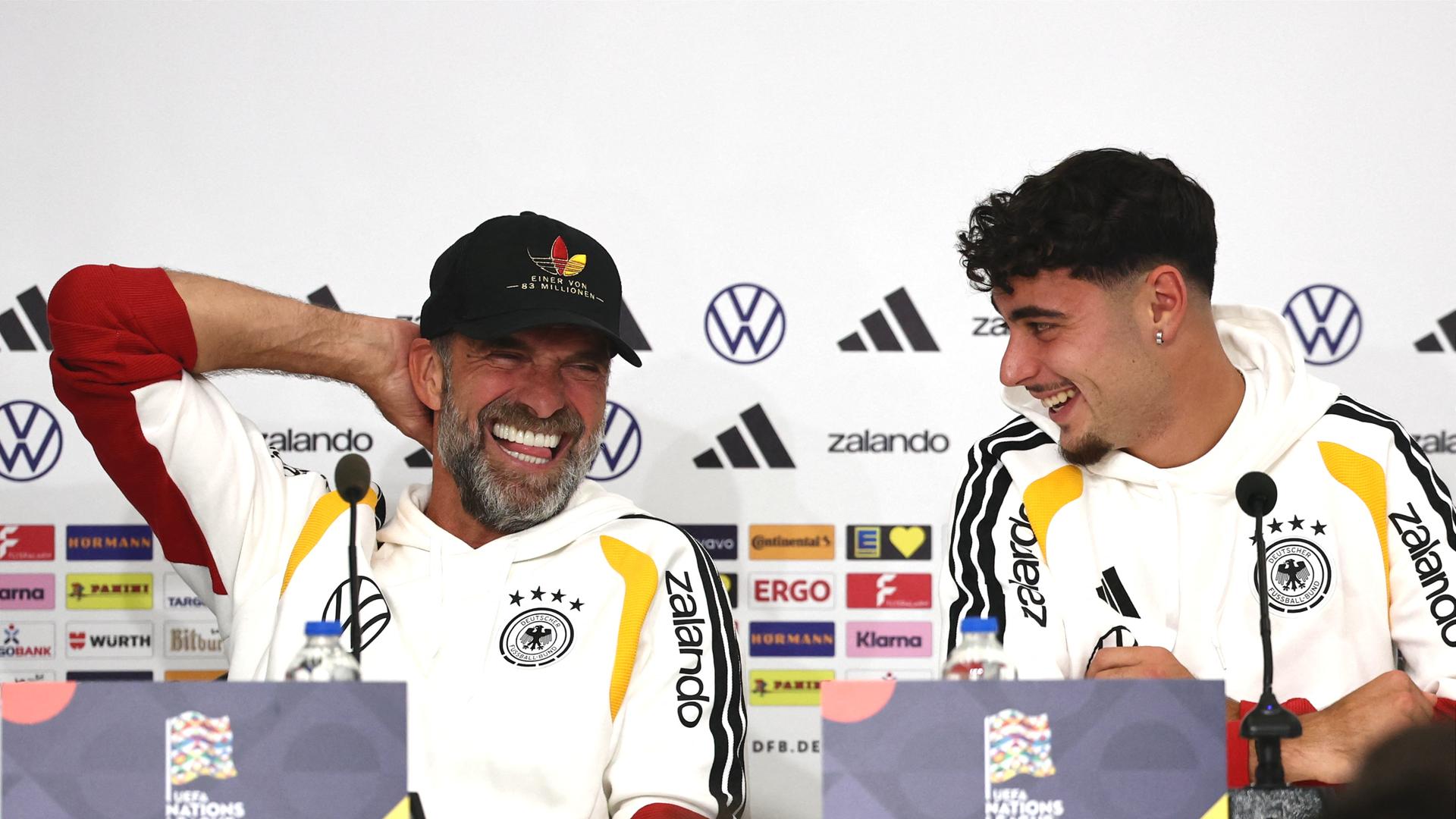 Pressekonferenz vor dem Spiel in Griechenland: Bundestrainer Jürgen Klopp (l) und Aleksandar Pavlovic stellen sich den Fragen der Journalisten. Sie tragen beide Deutschland-Trikots und lachen vergnügt.