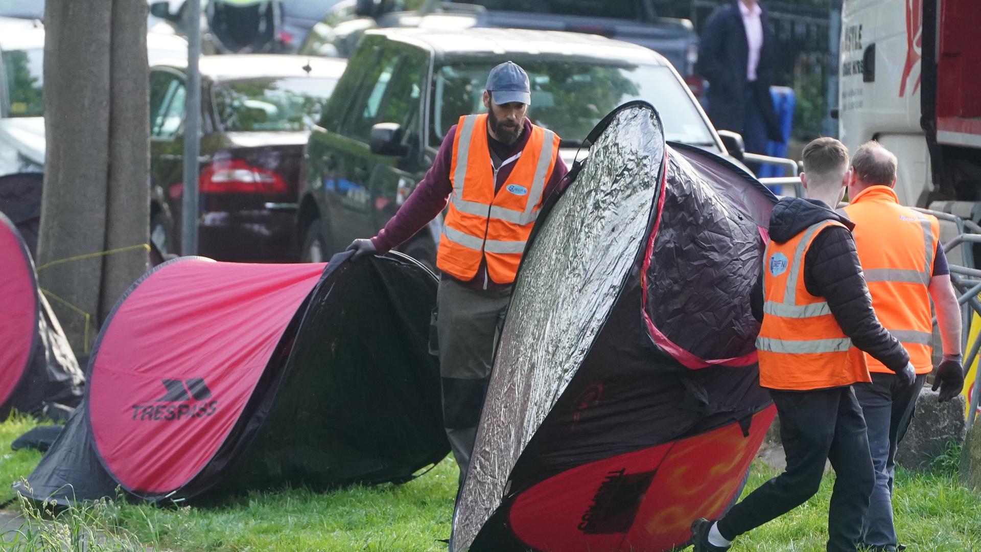 Arbeiter mit Warnwesten räumen Zelte beiseite.