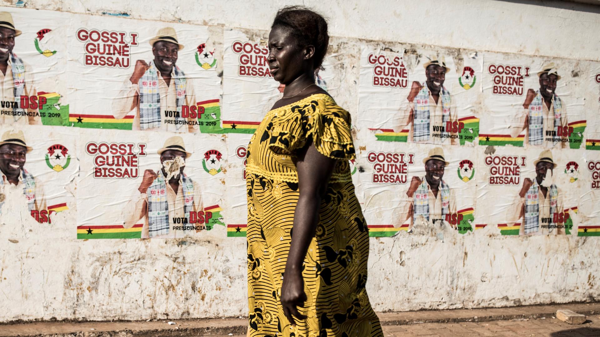 Eine Frau läuft an einem Wahlplakat in Guinea-Bissau vorbei.