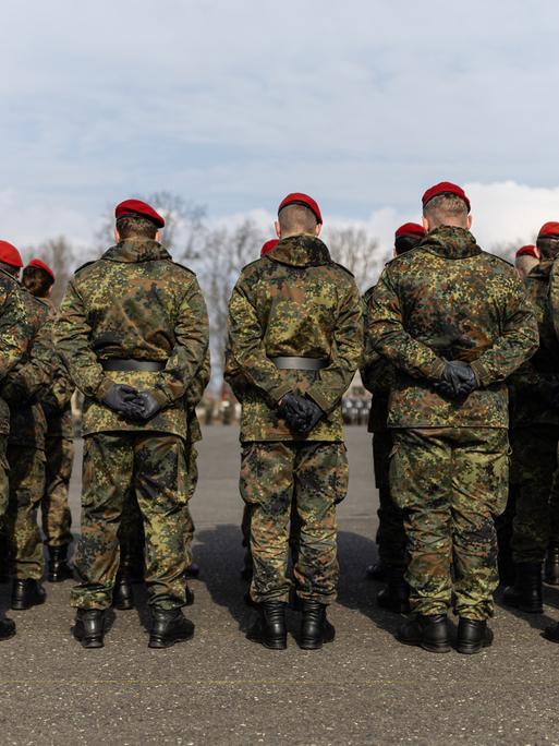 Mehrere Soldaten stehen auf einem Platz in einer Kaserne. 