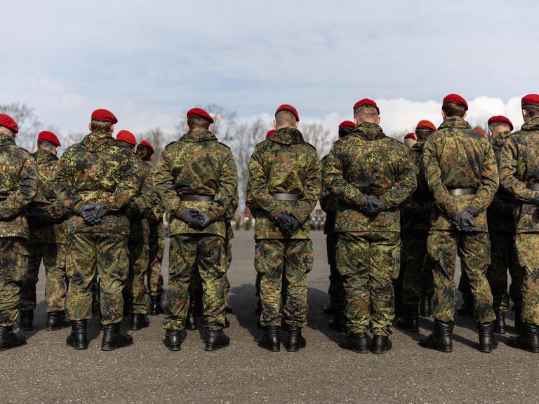 Mehrere Soldaten stehen auf einem Platz in einer Kaserne. 