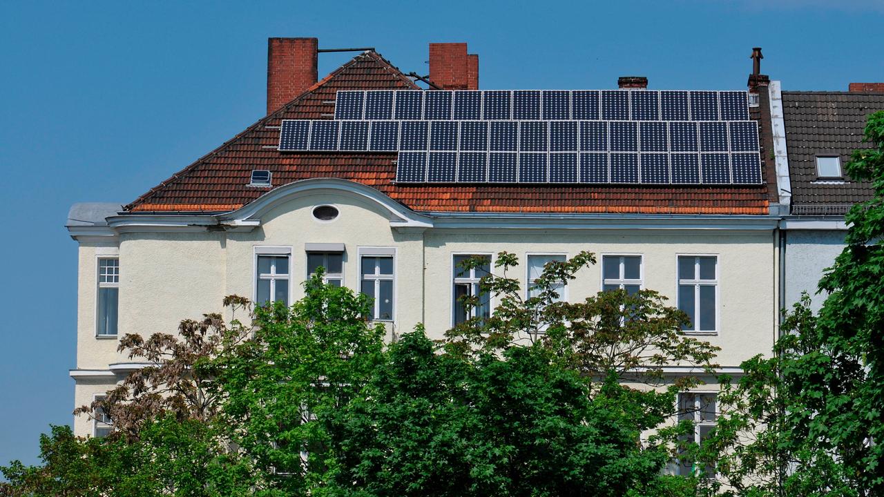 Auf dem Dach eines Berliner Altbaus sieht man Solarzellen.