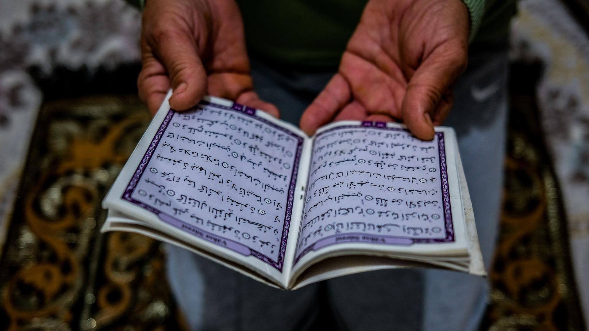 Türkei, Izmir: Eine männliche Hand hält ein Koran zum Lesen geöffnet.