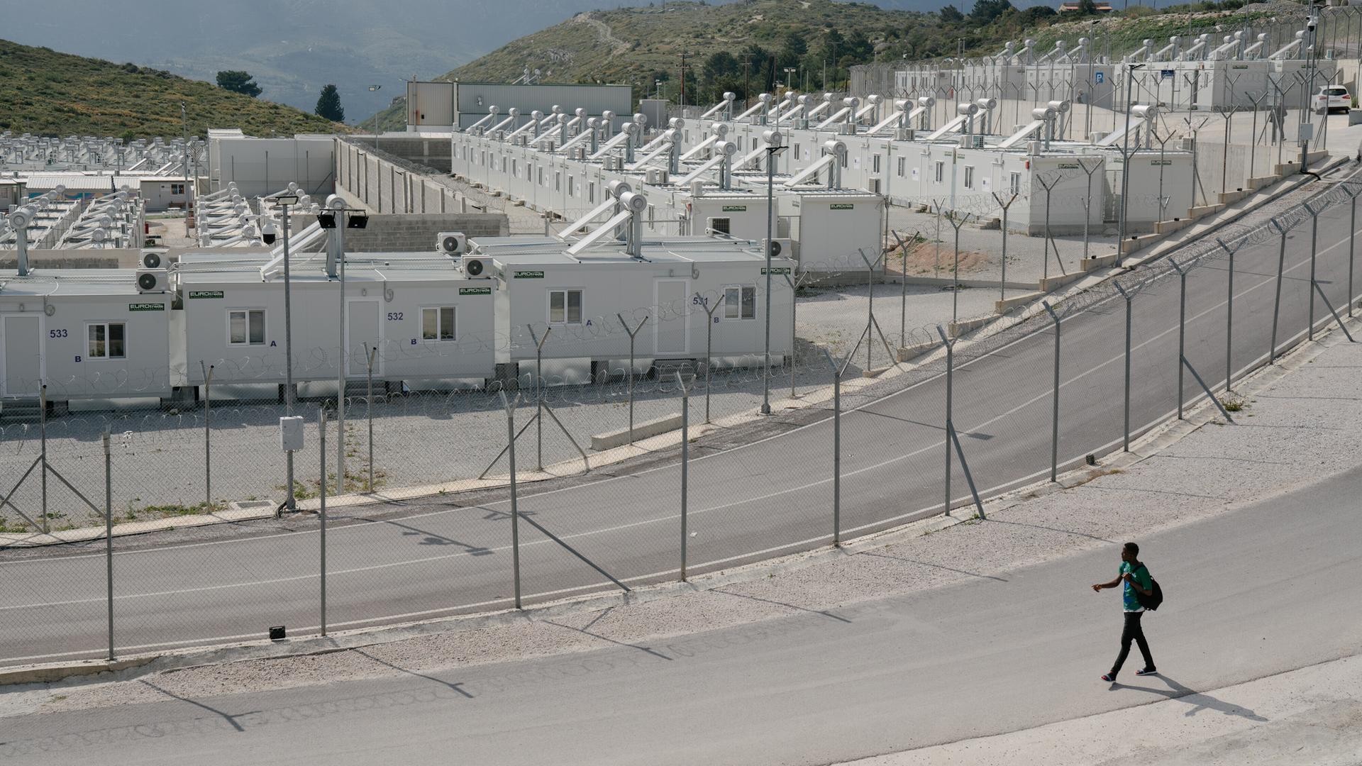 Eine eingezäunte Containersiedlung, im Hintergrund sind die Berge zu sehen. Eine eingezäunte Containersiedlung, im Hintergrund sind die Berge zu sehen.