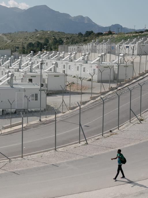 Eine eingezäunte Containersiedlung, im Hintergrund sind die Berge zu sehen.