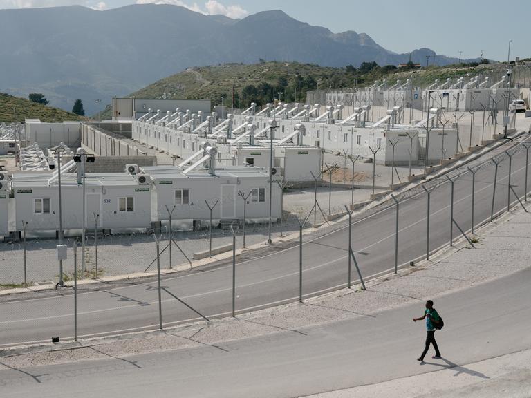 Eine eingezäunte Containersiedlung, im Hintergrund sind die Berge zu sehen.