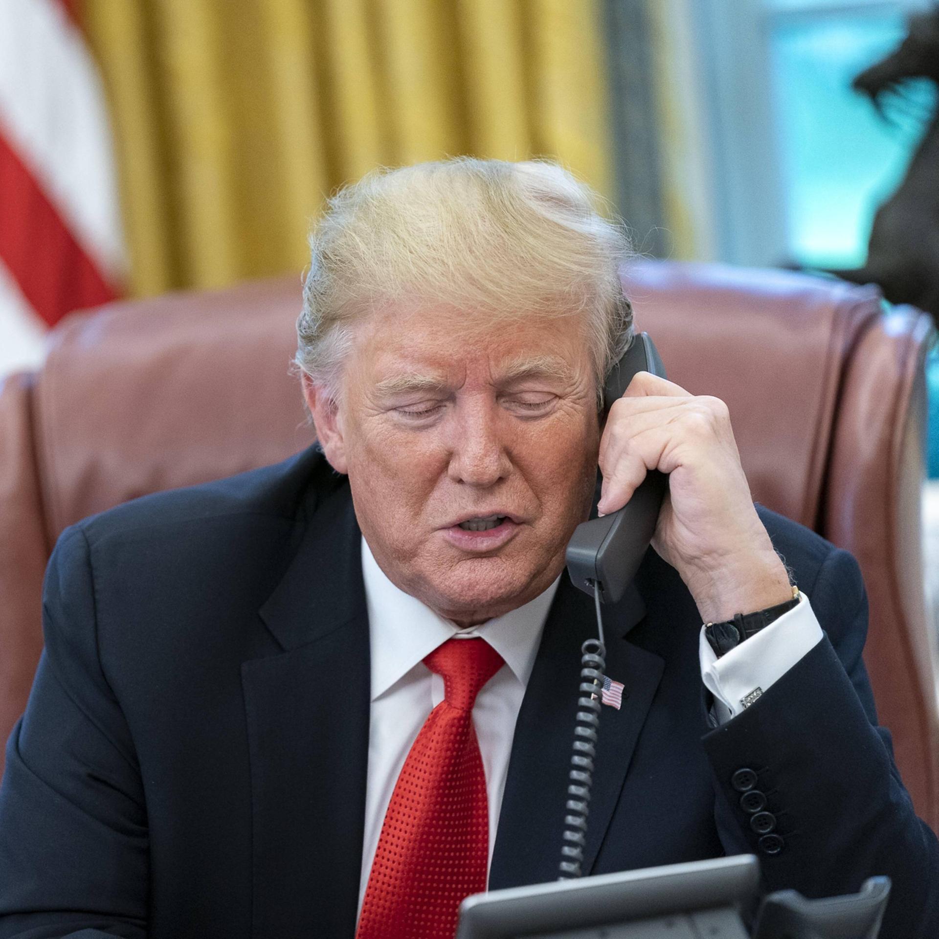 Donald Trump hat einen Telefon-Hörer in der Hand und spricht.