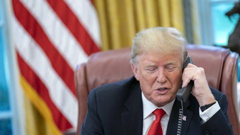 Donald Trump hat einen Telefon-Hörer in der Hand und spricht.