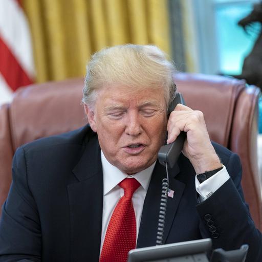 Donald Trump hat einen Telefon-Hörer in der Hand und spricht.