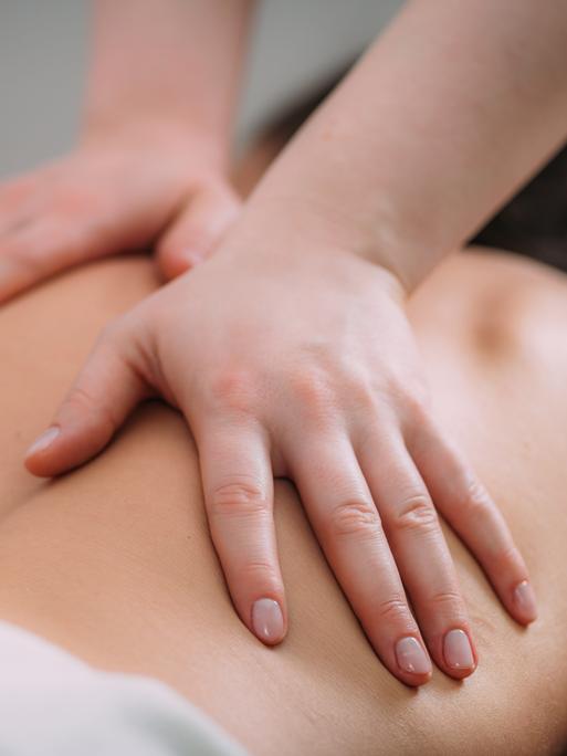Eine Person auf einer Liege bekommt eine Rückenmassage