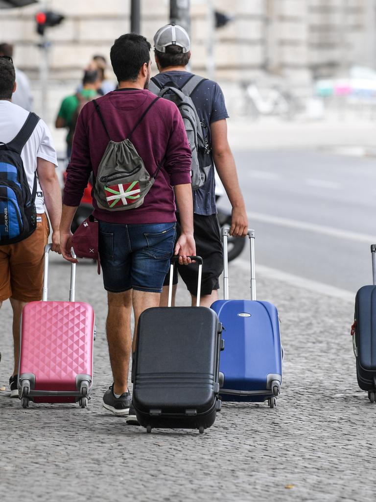 Touristen gehen mit Rollkoffern einen Gehweg in Berlin-Mitte entlang.