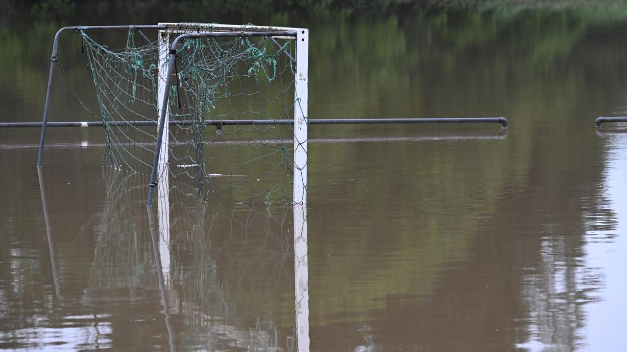 Ein Fußballtor spiegelt sich im Wasser auf einem überschwemmten Sportplatz. 