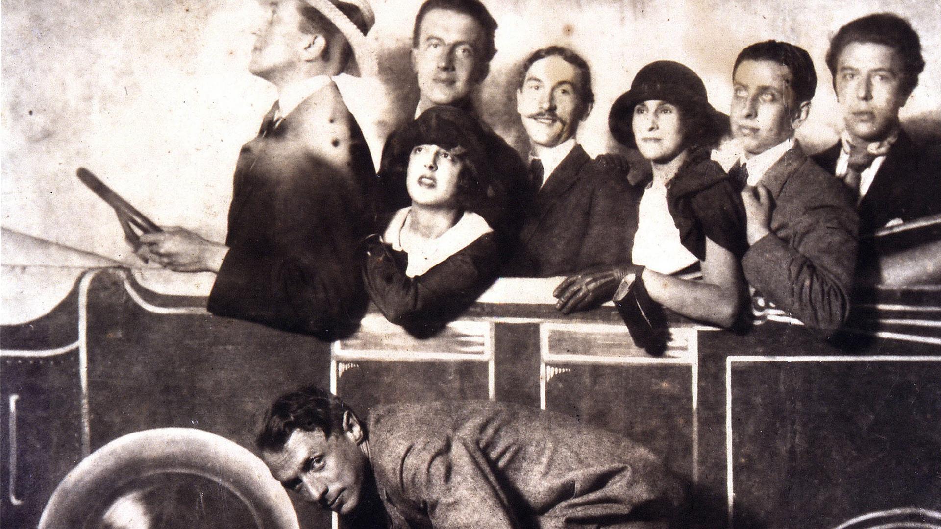 Max Morise, Simone Breton, Paul Eluard, Joseph Delteil, Gala Desnos, André Breton und Max Ernst (auf dem Fahrrad), auf dem Markt von Montmartre, 1923.