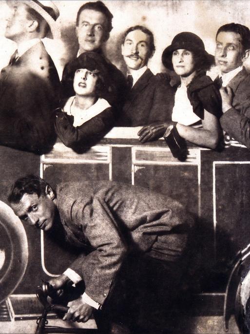 Max Morise, Simone Breton, Paul Eluard, Joseph Delteil, Gala Desnos, André Breton und Max Ernst (auf dem Fahrrad), auf dem Markt von Montmartre, 1923.