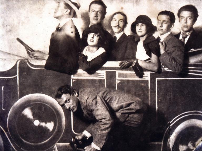 Max Morise, Simone Breton, Paul Eluard, Joseph Delteil, Gala Desnos, André Breton und Max Ernst (auf dem Fahrrad), auf dem Markt von Montmartre, 1923.