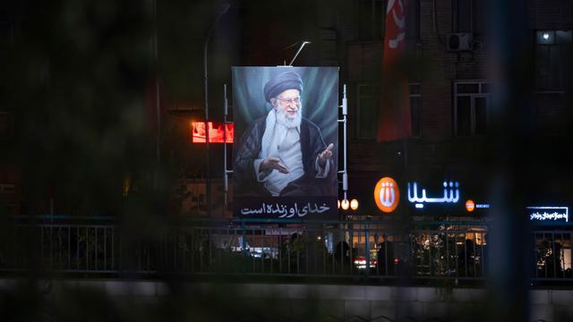 Ein beleuchtetes Porträt des am ersten Kriegstages getöteten geistlichen Führers, Ajatollah Ali Chamenei in den ansonsten größtenteils dunklen Straßen Teherans