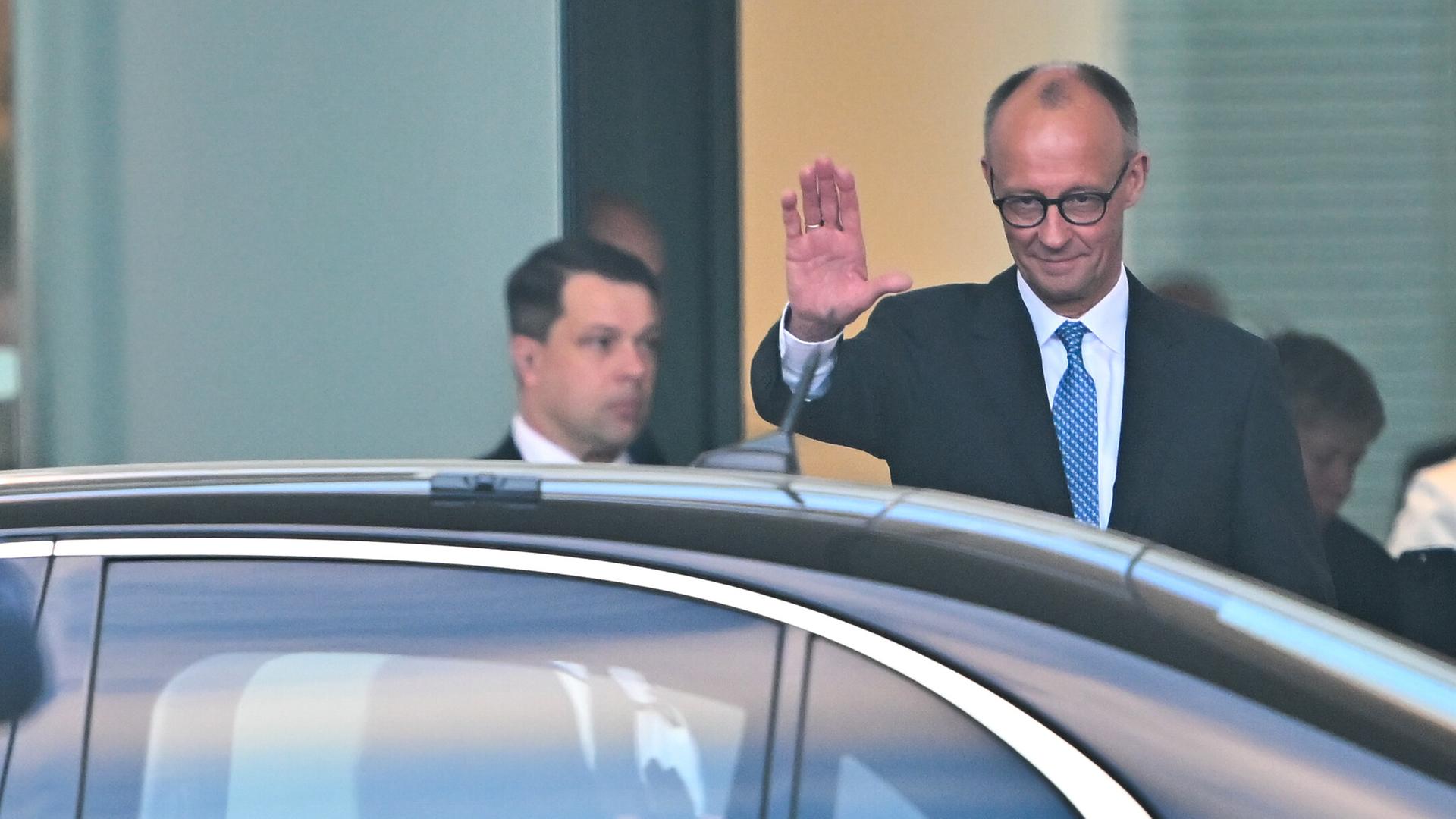 Der neu gewählte Bundeskanzler Friedrich Merz winkt nach der Amtsübergabe im Bundeskanzleramt seinem Vorgänger Olaf Scholz (SPD) zu, der im Wagen davon fährt. Der neu gewählte Bundeskanzler Friedrich Merz winkt nach der Amtsübergabe im Bundeskanzleramt seinem Vorgänger Olaf Scholz (SPD) zu, der im Wagen davon fährt.