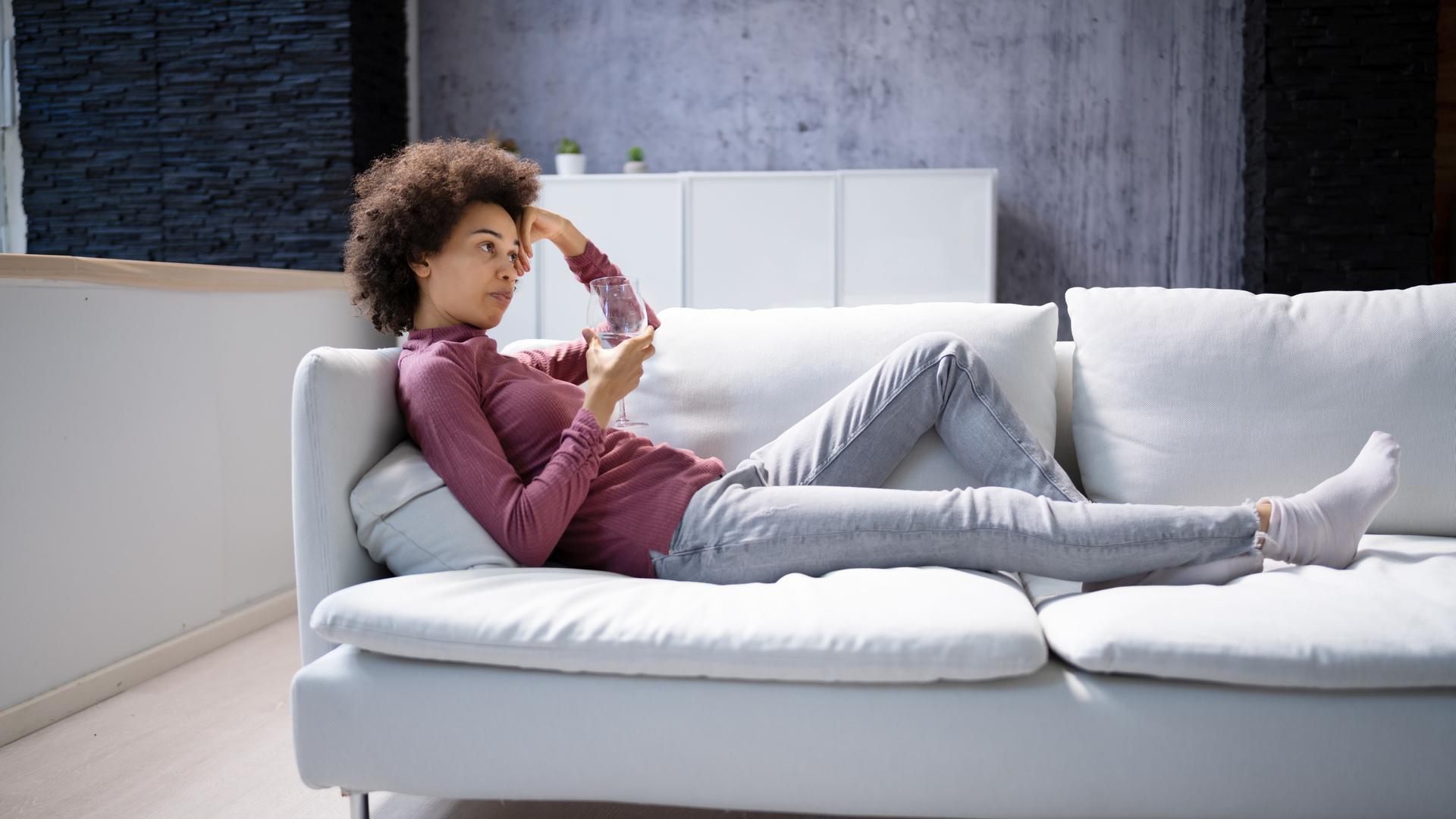 Eine junge Frau tagträumt auf einer Couch liegend. Eine junge Frau tagträumt auf einer Couch liegend.