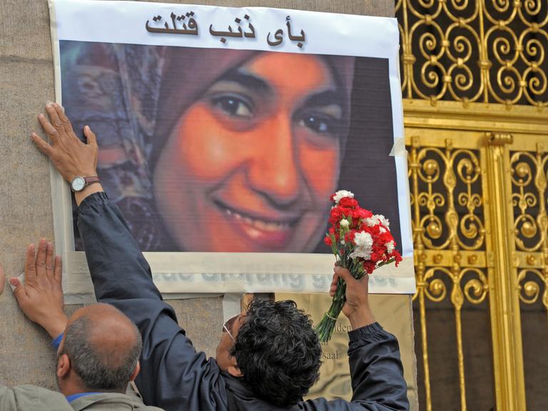 Vor dem Dresdner Rathaus kleben am Samstag (11.07.2009) zwei Männer ein Foto der am Mittwoch (01.07.2009) im Dresdner Landgericht erstochenen Ãgypterin Marwa El-Sherbini an die Wand.