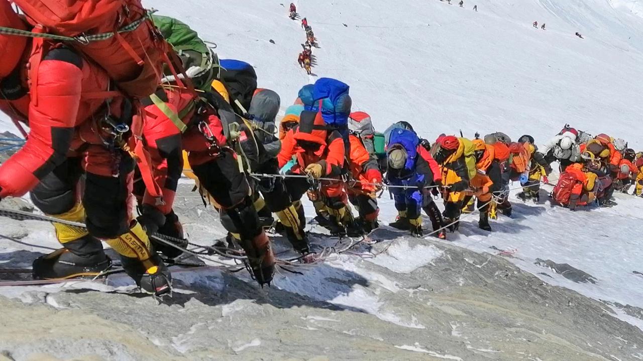Eine lange Schlange von Menschen steigt den Mount Everest hinauf.