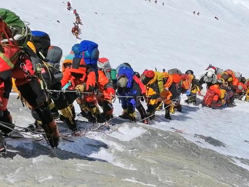 Eine lange Schlange von Menschen steigt den Mount Everest hinauf.