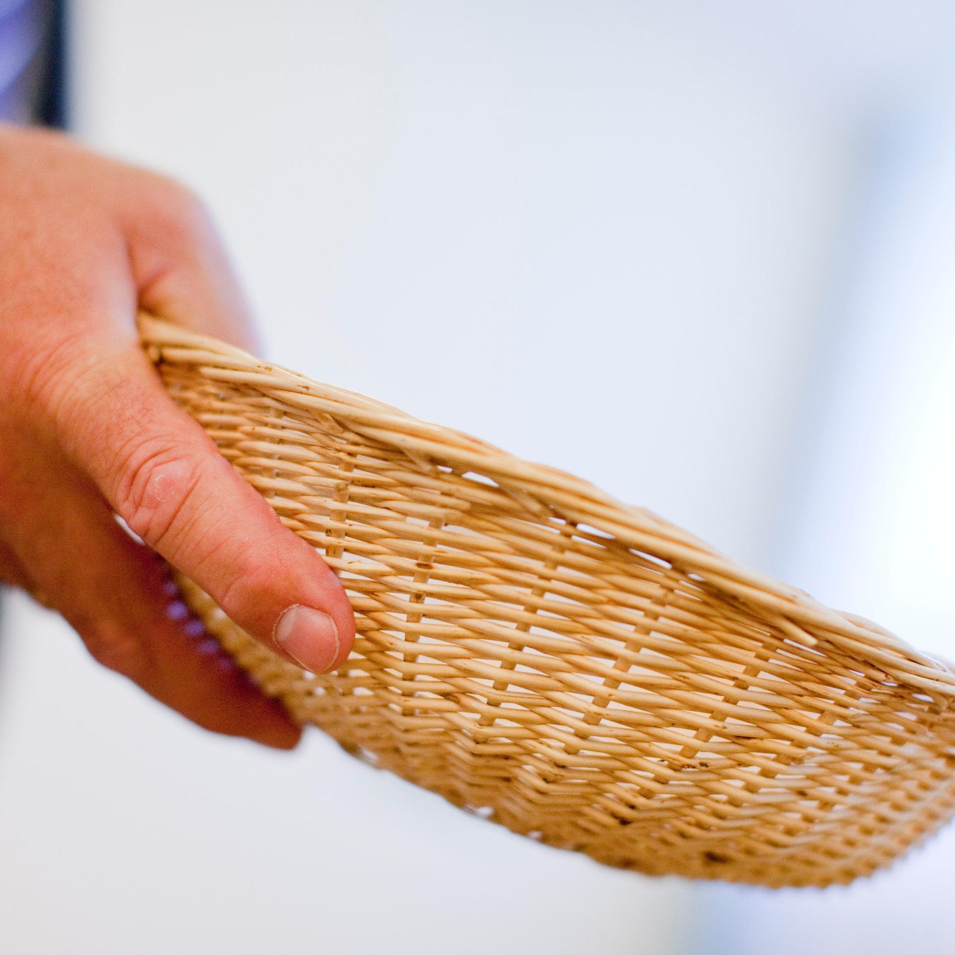 Eine Hand hält einen Spendenkorb.