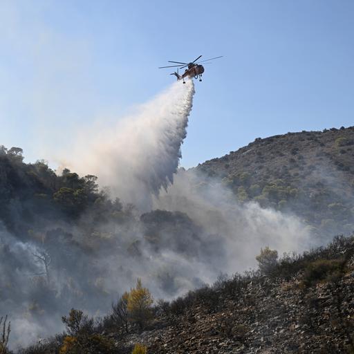 Ein Löschhubschrauber über einem Waldbrand.