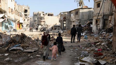 Inmitten zerstörter Gebäude laufen Passanten durch Gaza-Stadt.