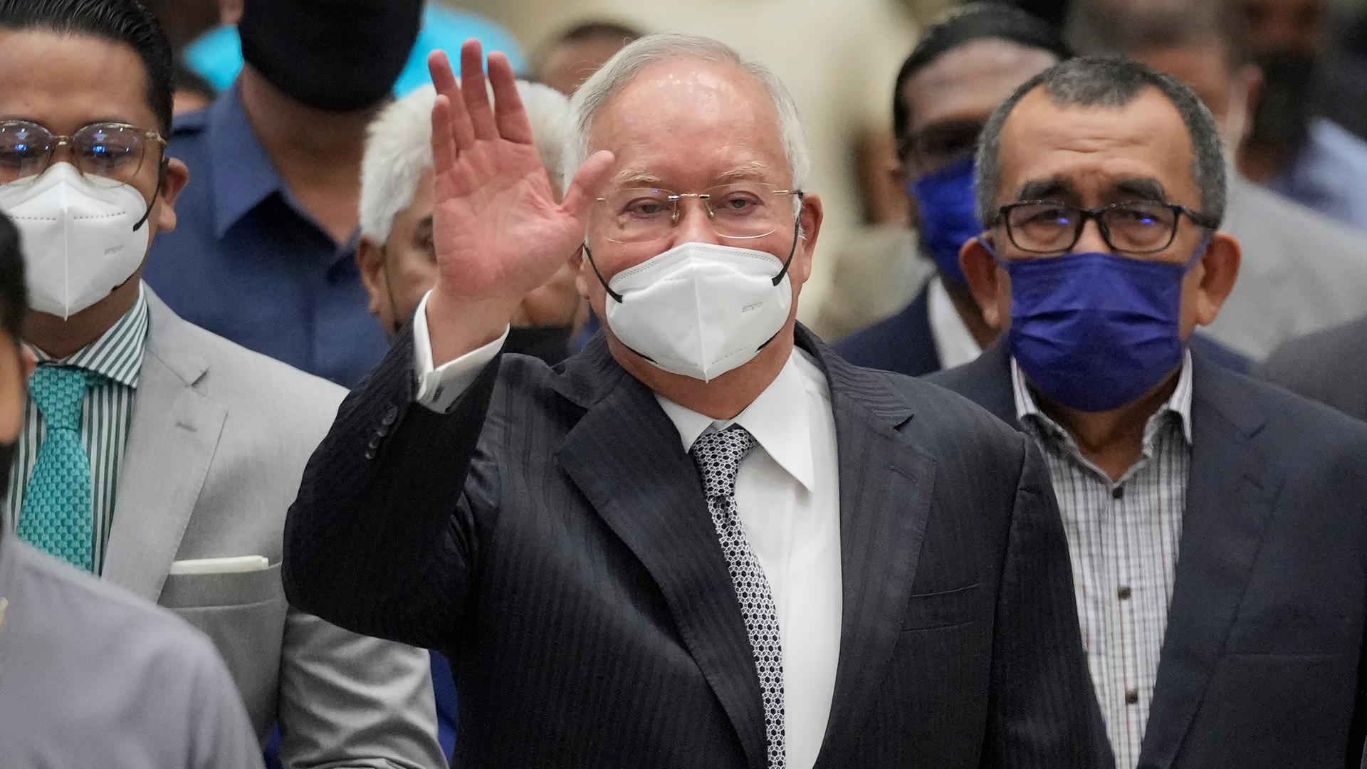 Najib Razak mit Maske winkt in die Kamera. Najib Razak mit Maske winkt in die Kamera.