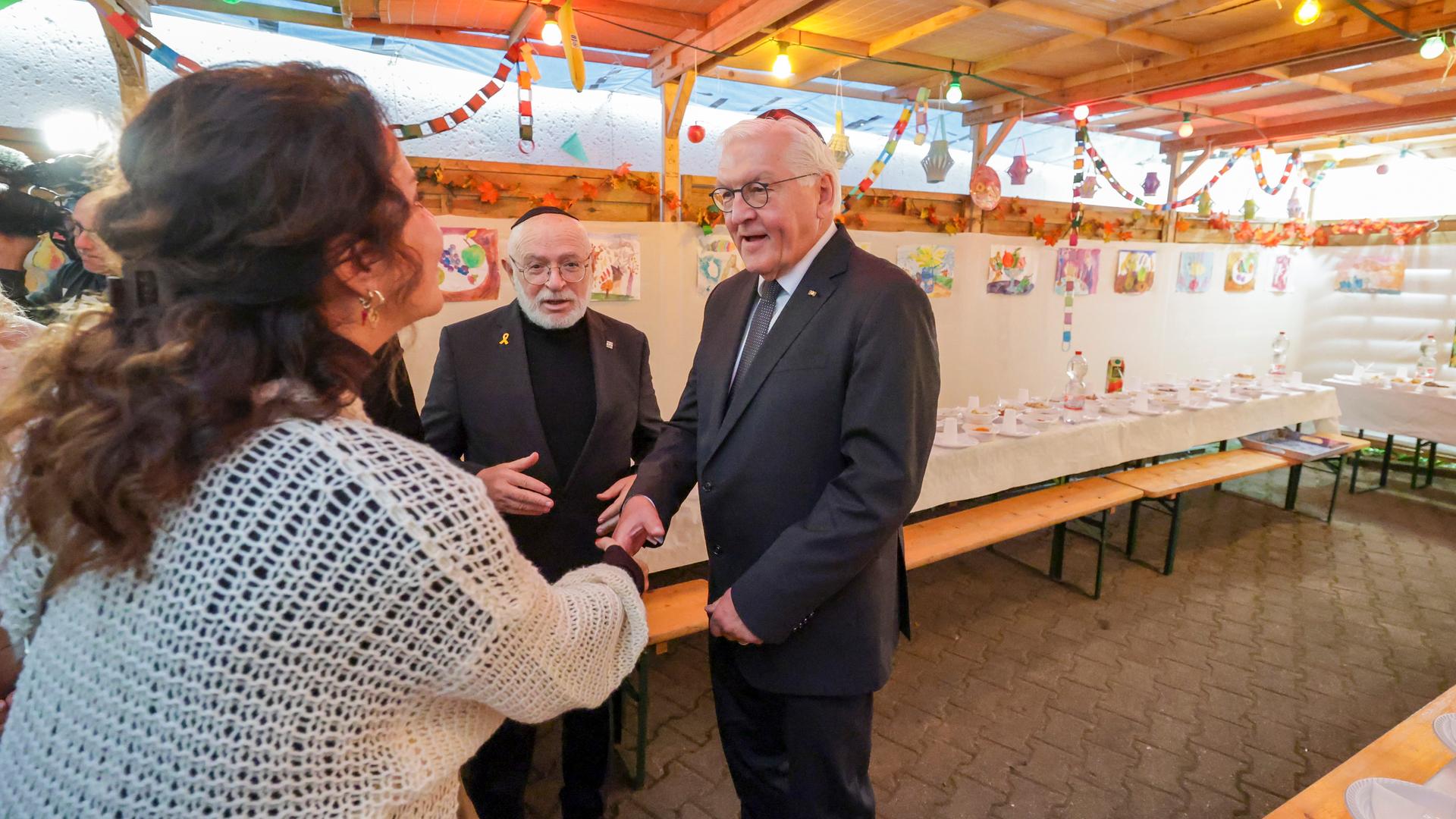 Bundespräsident Frank-Walter Steinmeier (r) wird von Küf Kaufmann und Marina Limperska von der Israelitischen Religionsgemeinde zu Leipzig in der Laubhütte nahe der Brodyer Synagoge empfangen, wo zum Laubhüttenfest Sukkot eingedeckt ist. 