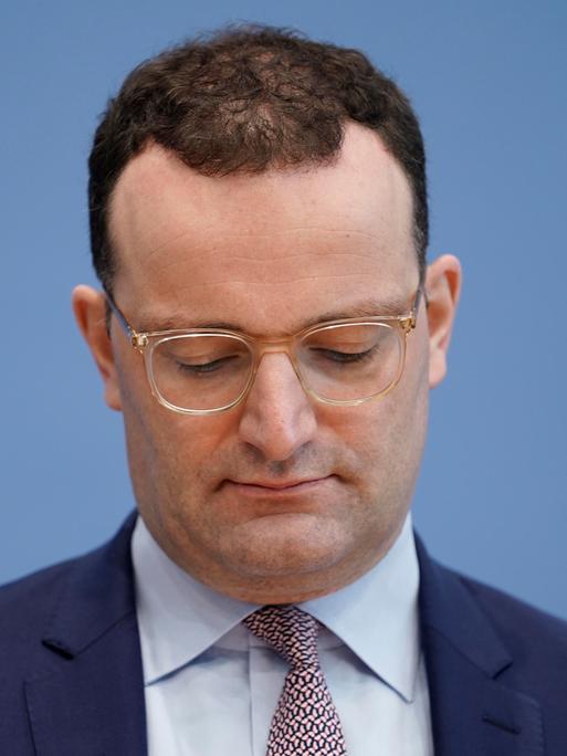 Jens Spahn im Porträt mit nach unten gesenktem Blick bei seiner letzten Bundespressekonferenz zum Thema Corona-Lage als Bundesgesundheitsminister am 3.12.2021