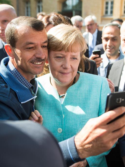 Bundeskanzlerin Angela Merkel nach dem Besuch einer Erstaufnahmeeinrichtung für Asylbewerber der Arbeiterwohlfahrt (AWO) und der Außenstelle des Bundesamtes für Migration und Flüchtlinge in Berlin-Spandau mit einem Flüchtling 