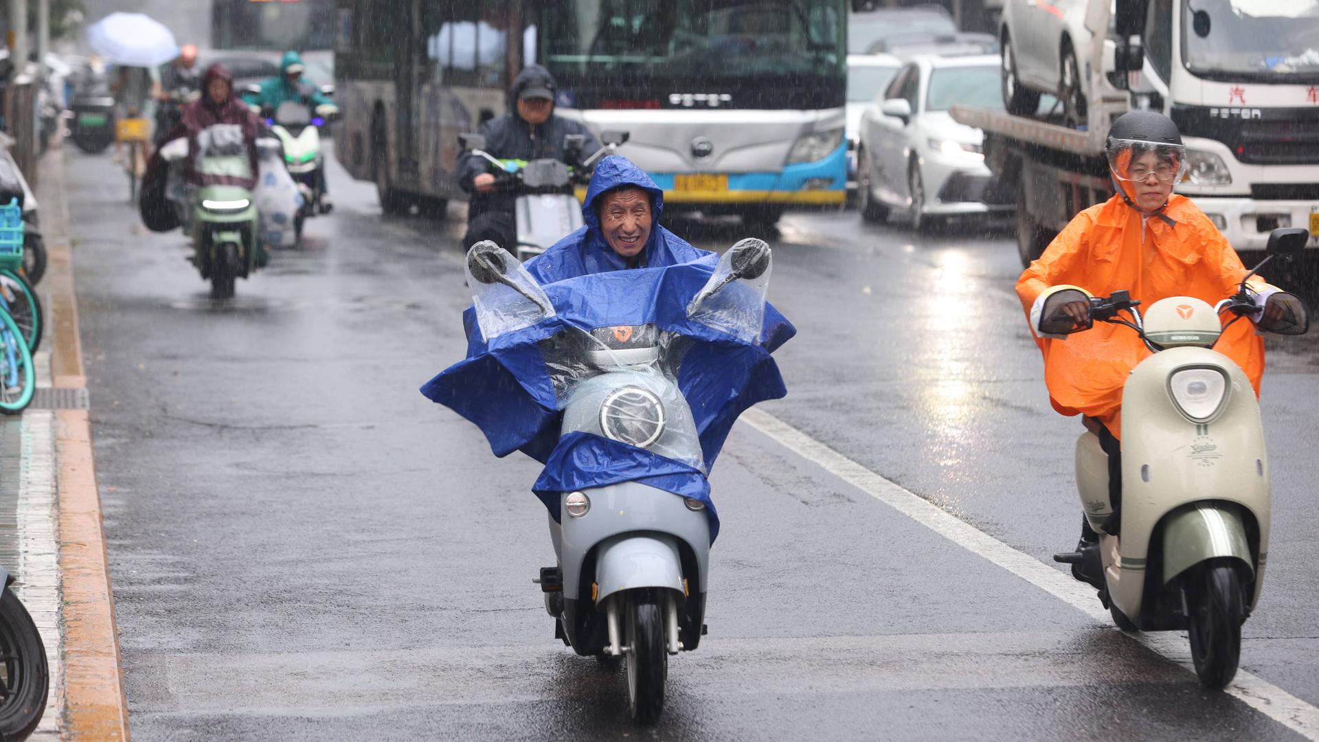 Männer mit Regenkleidung auf Motorrollern in Chinas Hauptstadt Peking Männer mit Regenkleidung auf Motorrollern in Chinas Hauptstadt Peking