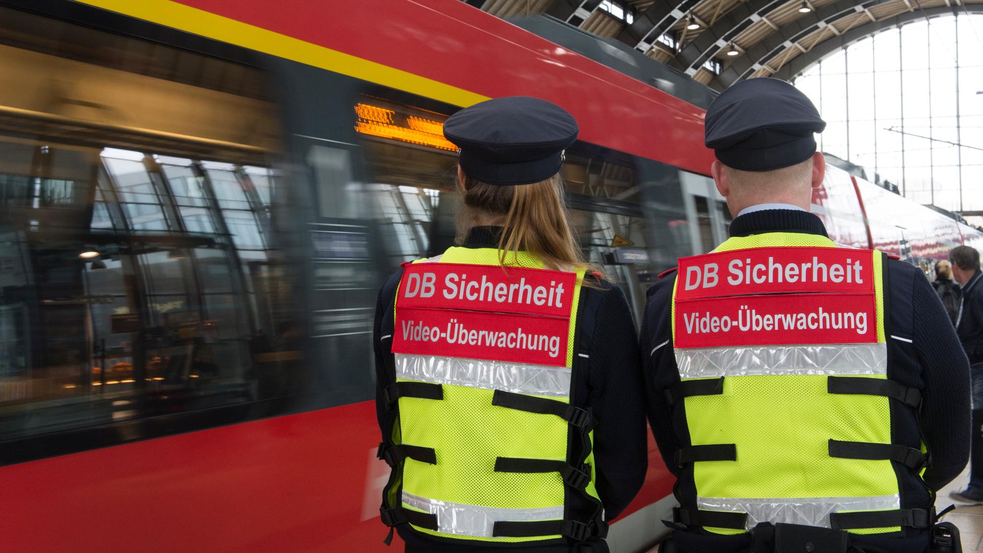Sicherheitsmitarbeiter der Deutschen Bahn gehen 2016 bei einem Pressetermin in Berlin mit Spezialwesten mit der Aufschrift «DB Sicherheit Videoüberwachung» und einer daran angebrachten Mini-Kamera über einen Bahnsteig im Bahnhof Alexanderplatz. Sicherheitsmitarbeiter der Deutschen Bahn gehen 2016 bei einem Pressetermin in Berlin mit Spezialwesten mit der Aufschrift «DB Sicherheit Videoüberwachung» und einer daran angebrachten Mini-Kamera über einen Bahnsteig im Bahnhof Alexanderplatz.