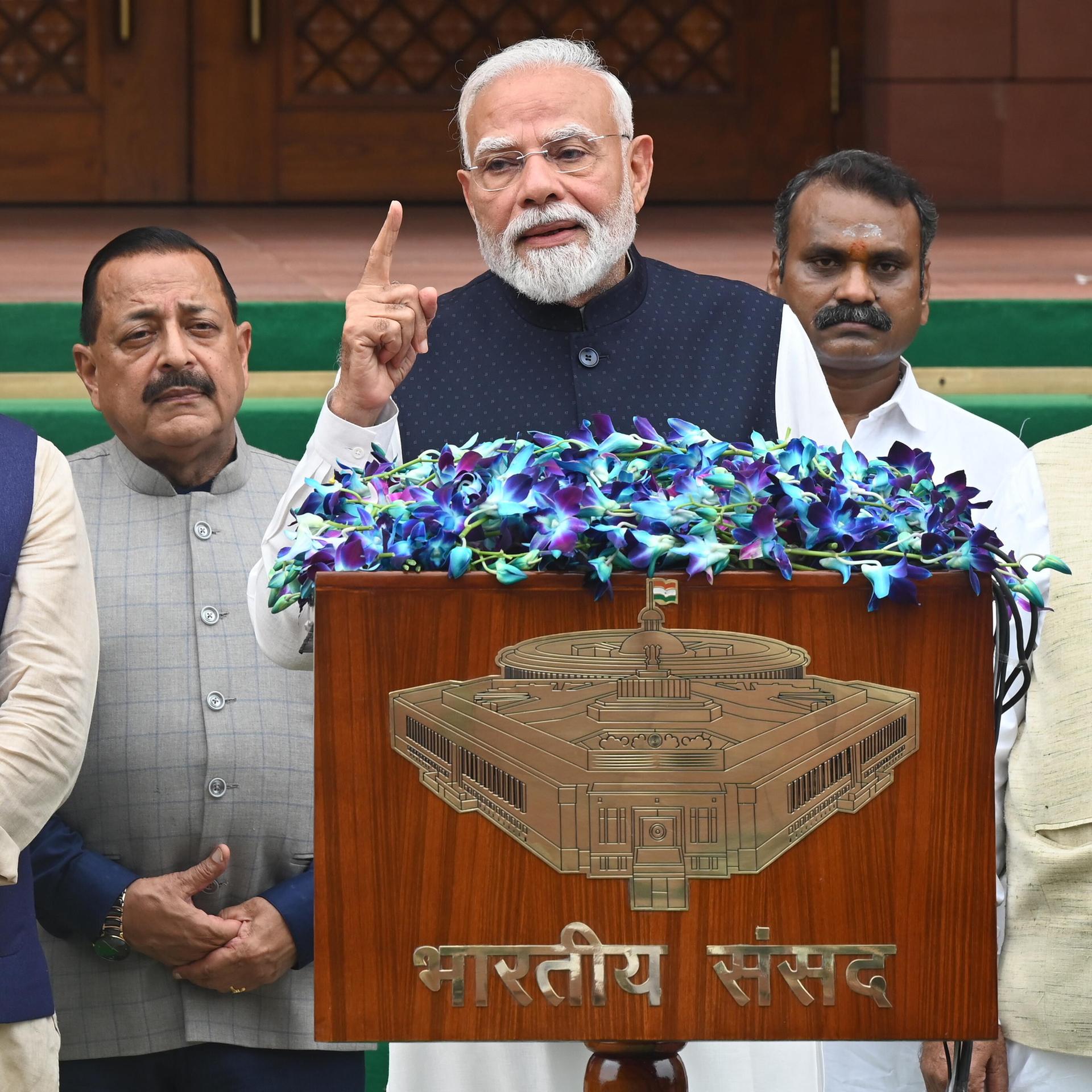 Indiens Premierminister Narendra Modi steht hinter einem Rednerpult und hebt den rechten Zeigefinger.