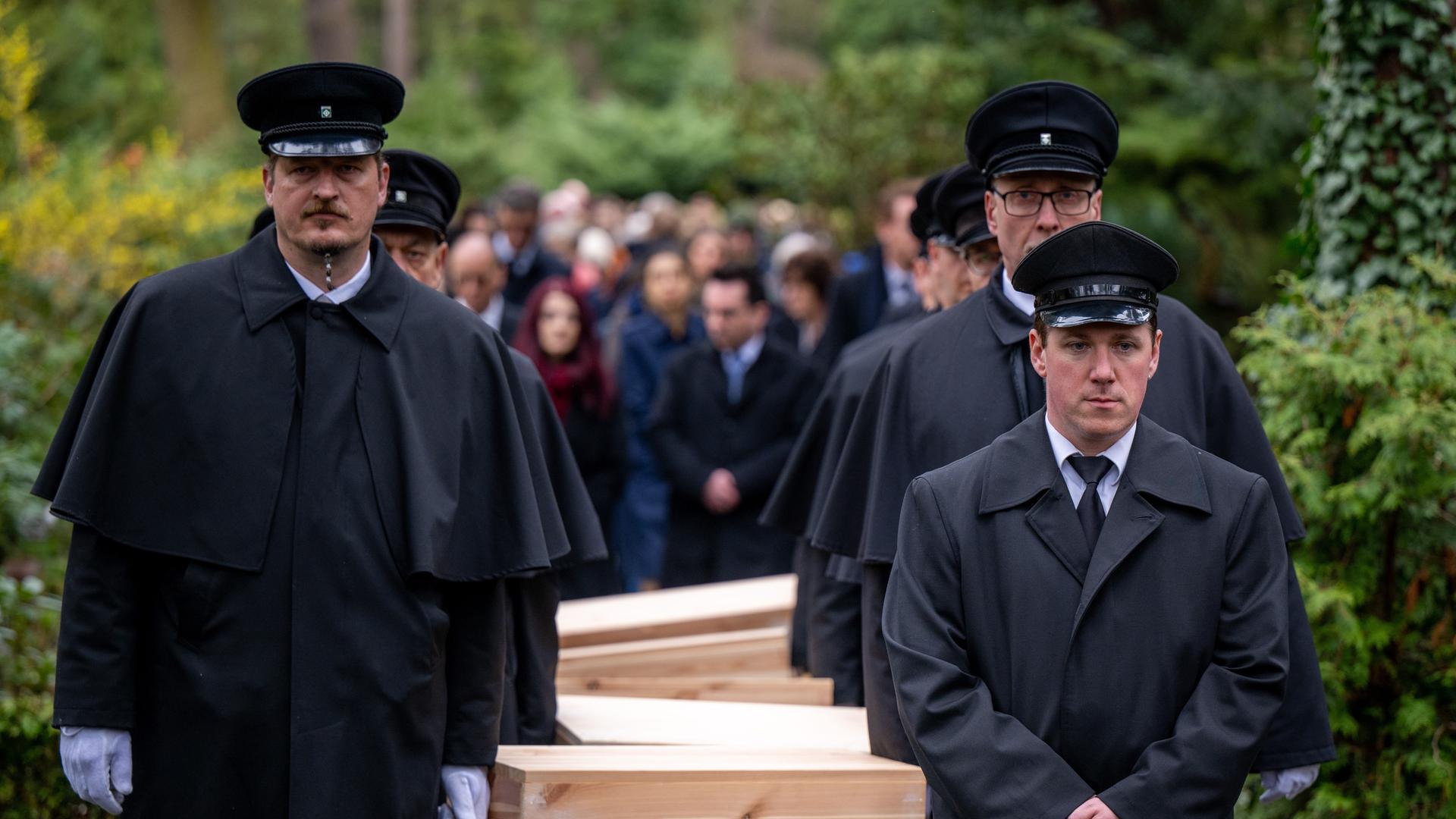 Gebeinekisten mit menschlichen Knochen werden nach der Trauerfeier zur Grabstätte auf dem Waldfriedhof Dahlem getragen.