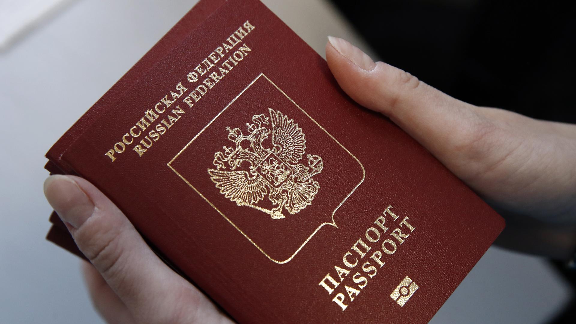 Eine Hand hält mehrere russische Reisepässe. Eine Hand hält mehrere russische Reisepässe.