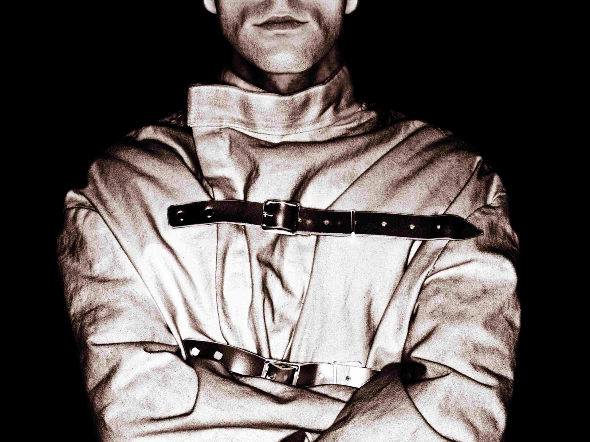 Schwarz-Weiß-Bild eines Manns mit Zwangsjacke