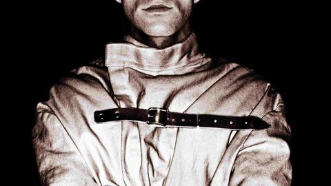 Schwarz-Weiß-Bild eines Manns mit Zwangsjacke