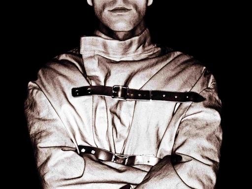 Schwarz-Weiß-Bild eines Manns mit Zwangsjacke