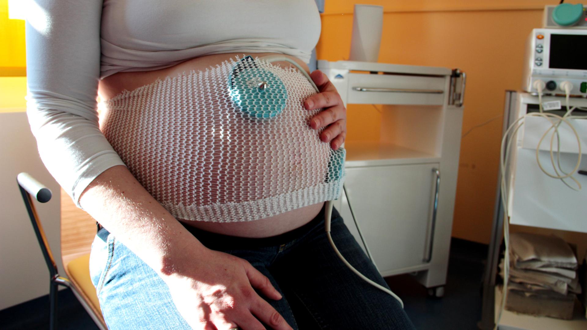 Ein Wehenschreiber misst am Bauch einer Hochschwangeren 