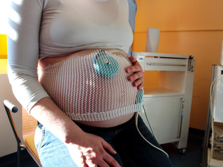Ein Wehenschreiber misst am Bauch einer Hochschwangeren 
