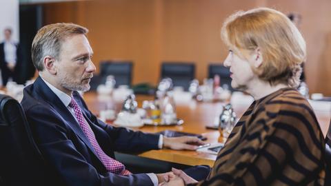 Finanzminister Christian Lindner (FDP) und Familienministerin Lisa Paus sitzen an einem ovalen Tisch nebeneinander und schauen sich an