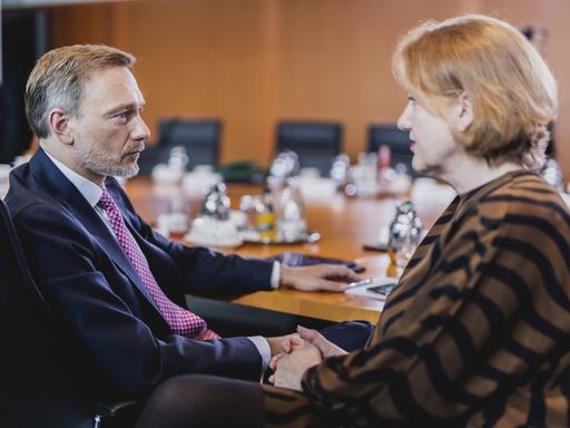 Finanzminister Christian Lindner (FDP) und Familienministerin Lisa Paus sitzen an einem ovalen Tisch nebeneinander und schauen sich an