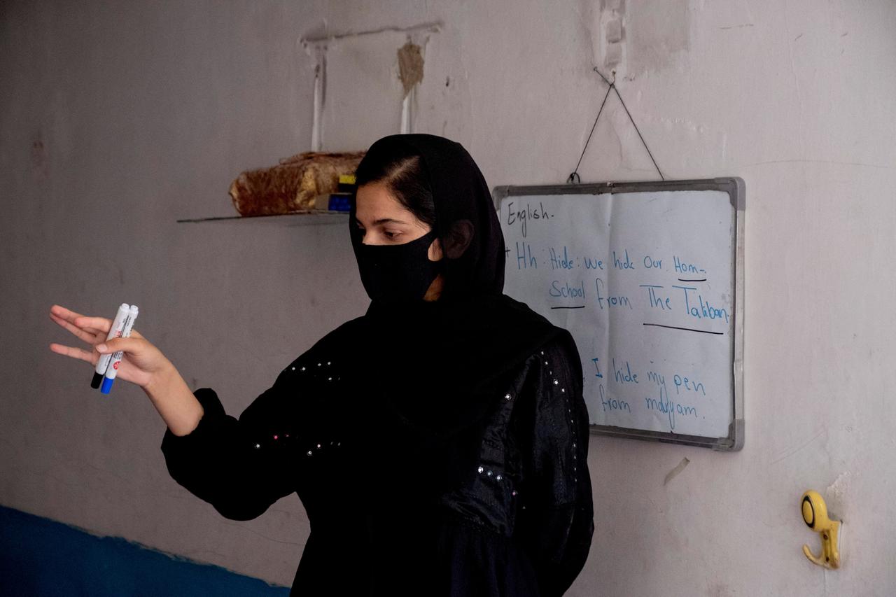 Eine verhüllte Lehrerin, auf einer Tafel stehen englische Sätze, u.a.: "Wir verstecken unseren Privatunterricht vor den Taliban"